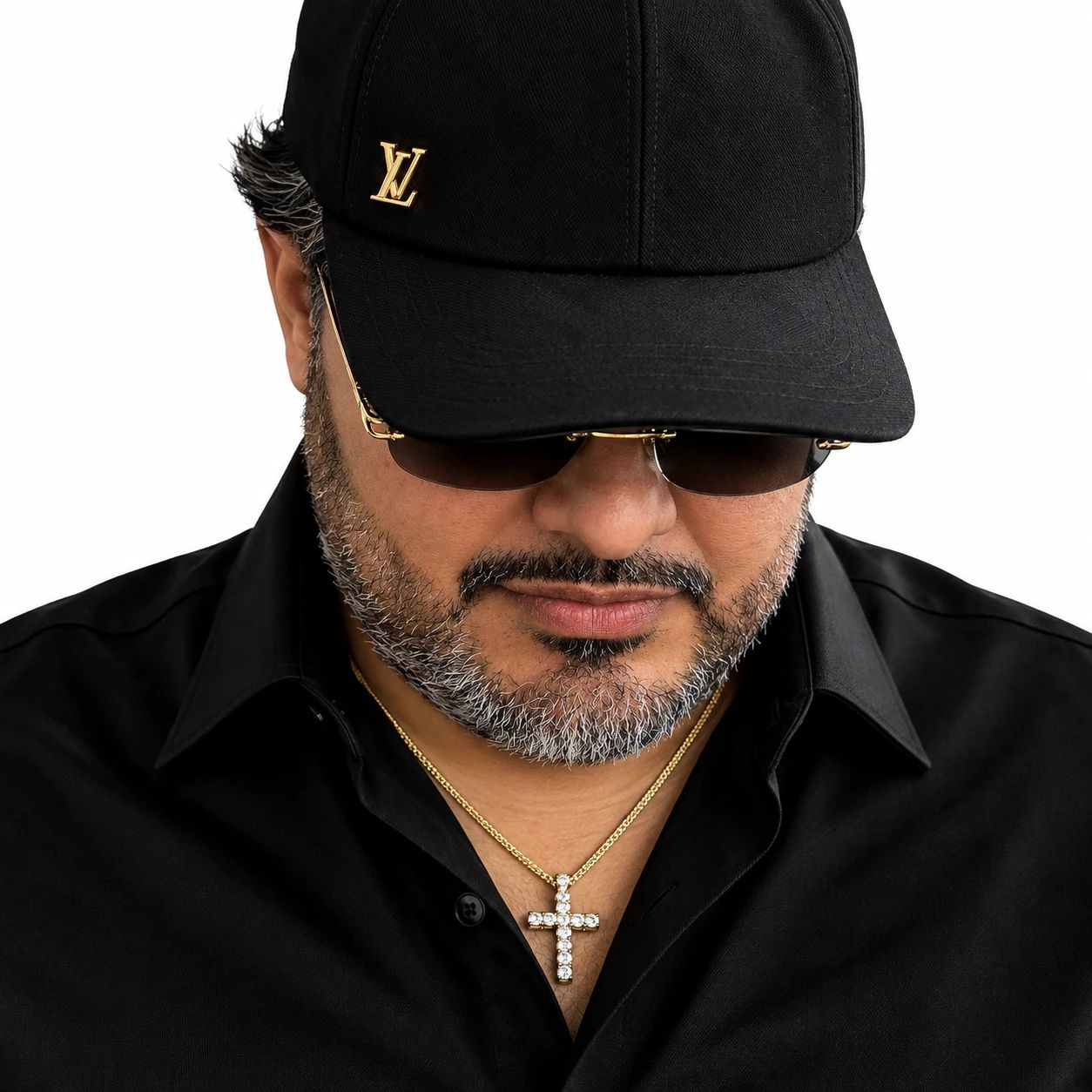 Aflo mirando hacia abajo, con gorra negra, lentes oscuros y camisa negra.